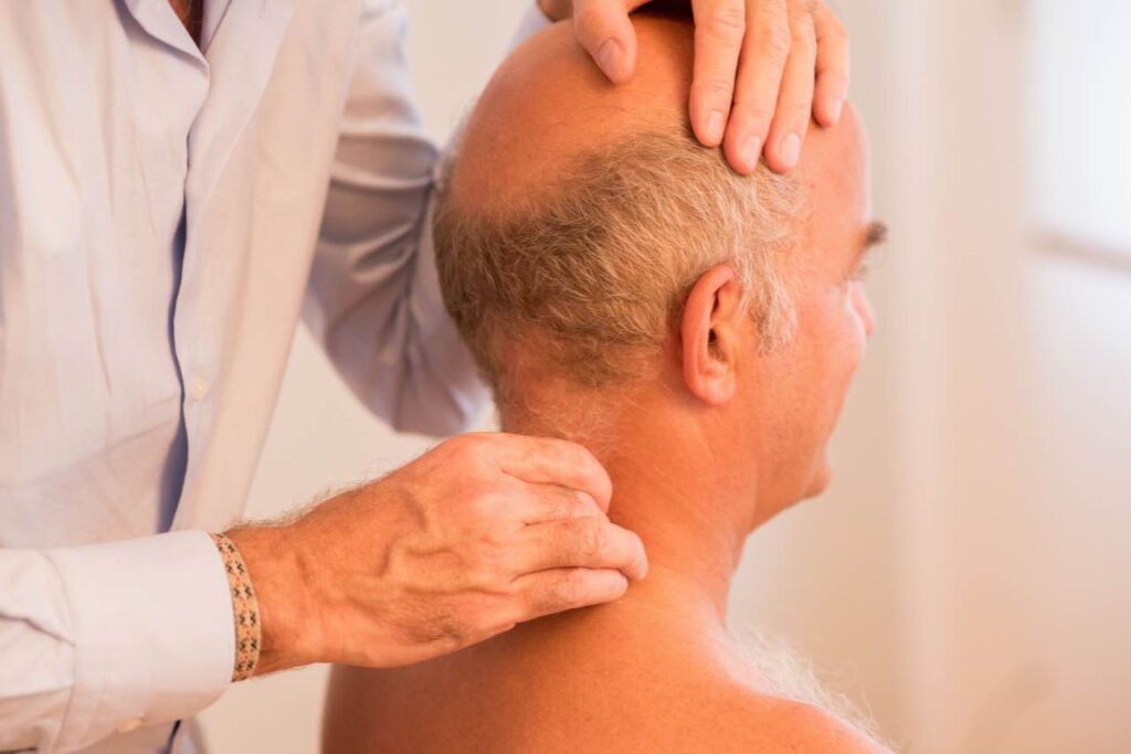 Therapeut massiert Nacken eines Mannes