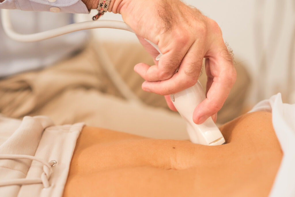 Arzt führt Ultraschall am Bauch durch
